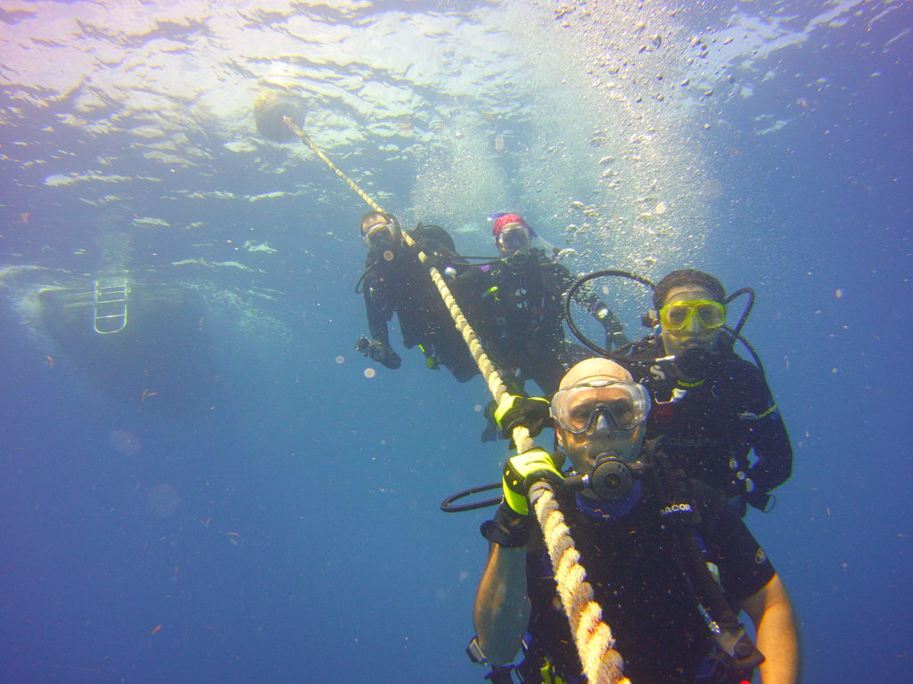 SCUBA Divers hanging on line on underwater safety stop